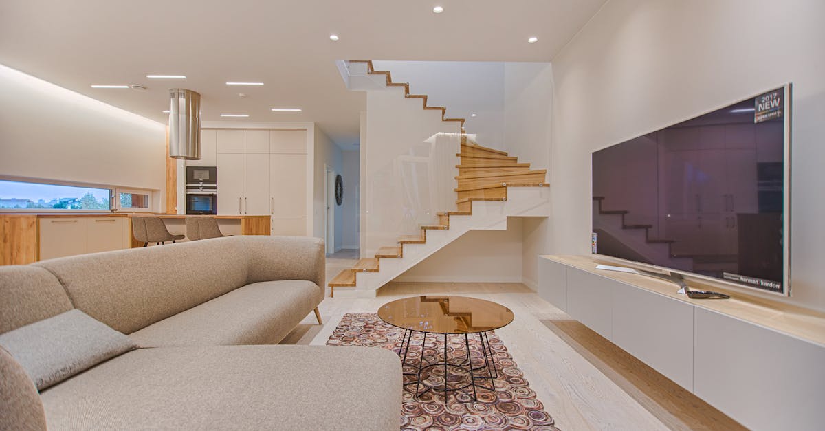 Spacious modern living room featuring stairs, a TV, and sleek furniture design.